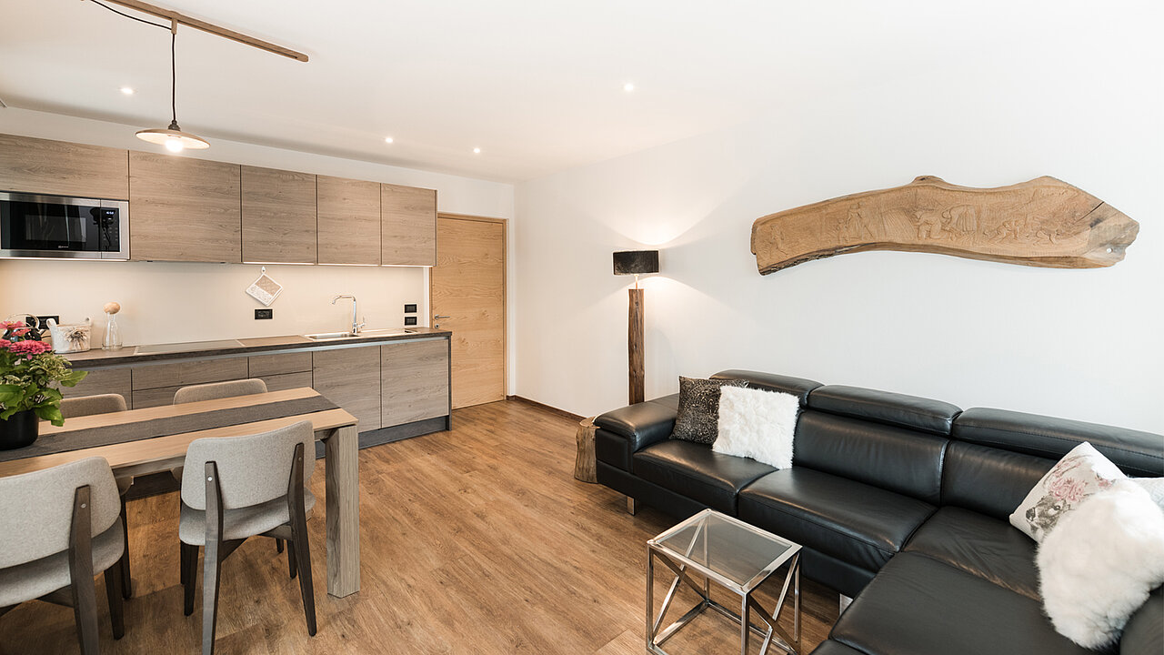Wohnbereich mit komplett eingerichteter Küche, Esstisch und Couch des Apartments Saslonch in St. Ulrich