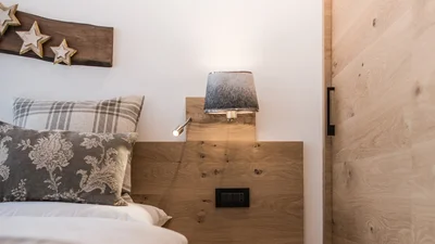 Bed and nightstand of the double bedroom of the apartment Seceda in Ortisei