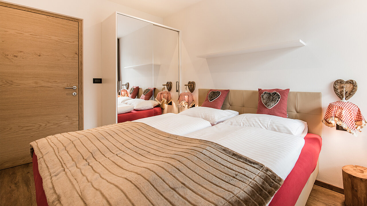 Bett und Schrank im Schlafzimmer des Apartments Sella in St. Ulrich