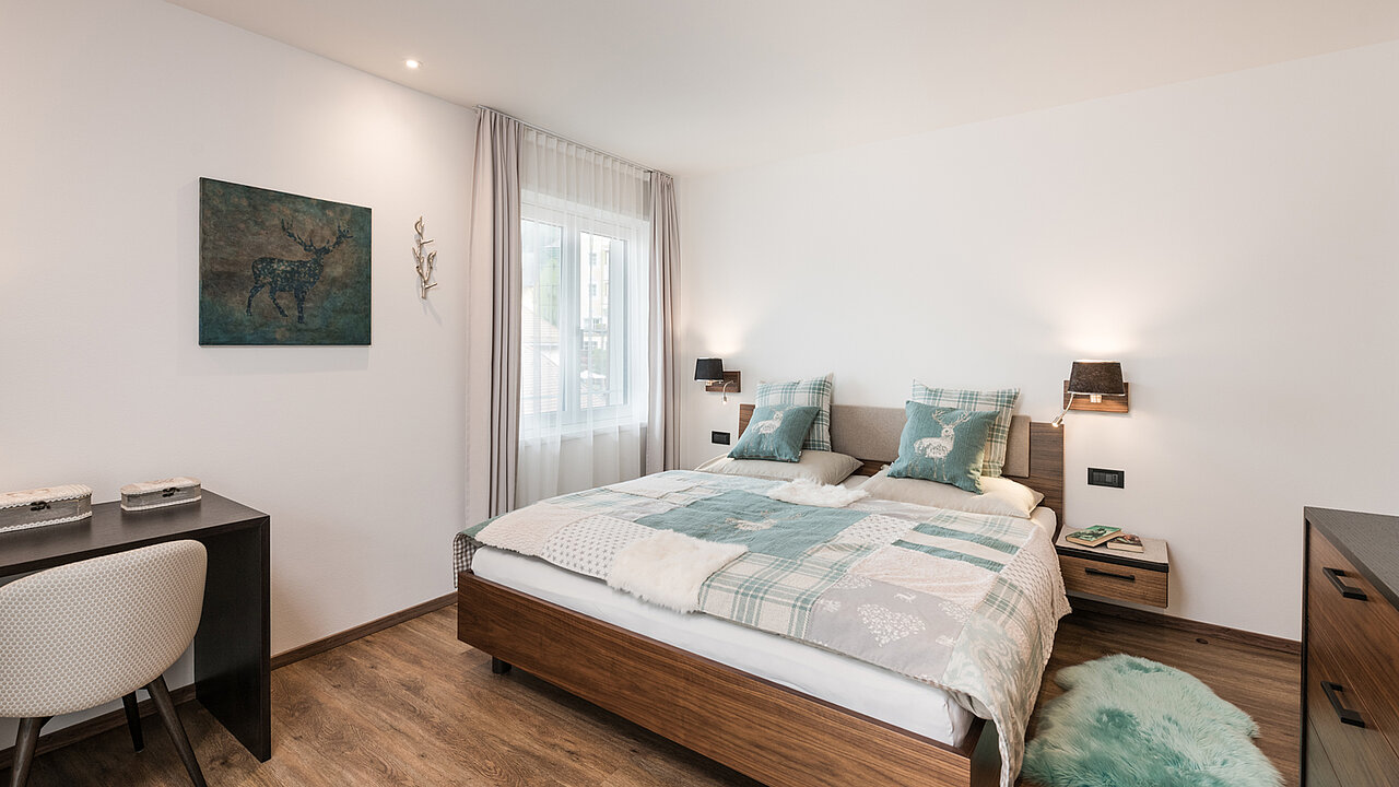 Bett und Fenster des Doppelzimmers des Apartments Saslonch in St. Ulrich