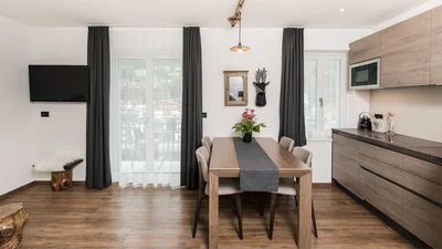 Kitchen, dining table and balcony door of the living area of the apartment Saslonch in Ortisei 