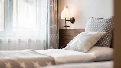 Bed and window of the twin bedroom of the apartment Saslonch in Ortisei 
