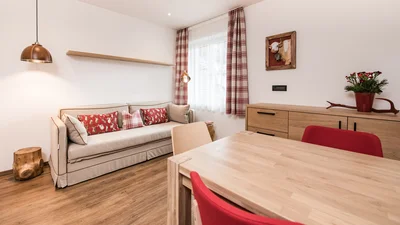 Dining table, sofa, and window of the living area of the apartment Sella in Ortisei