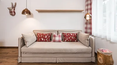 Sofa and window of the living area of the apartment Sella in Ortisei